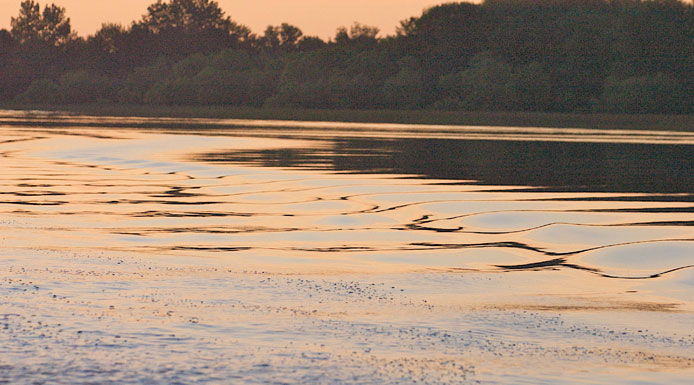 Lumière rosée du soleil levant réfléchie sur l’eau.