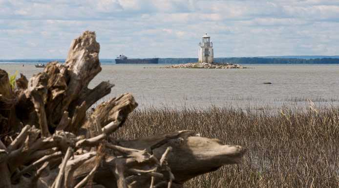 Navire dans le chenal de navigation passant près d’un phare au lac Saint-Pierre.